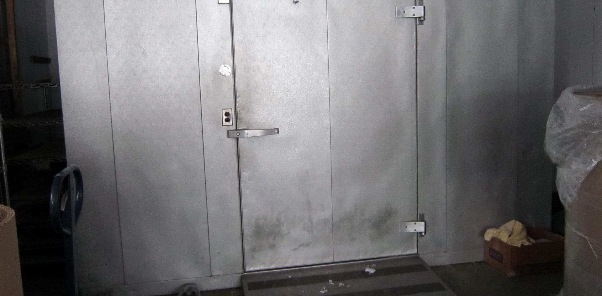 Technician installing commercial walk-in cooler refrigeration system in Calgary restaurant